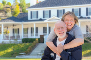 Attractive Happy Senior Couple in Front Yard of House.