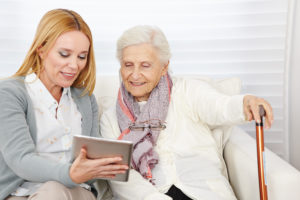 Woman giving senior woman introduction to internet with a tablet computer
